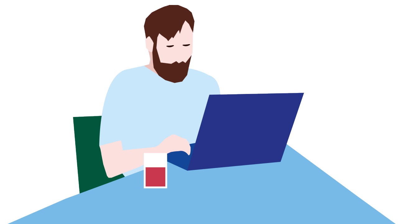 Man med brunt hår och skägg skriver på en laptop. På bordet har han ett glas med saft.