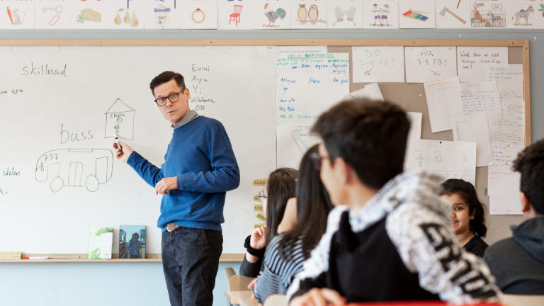 en lärare förklarar en uppgift för barn i ett klassrum