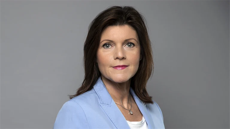 Arbetsmarknadsminister Eva Nordmark i ljusblå kavaj mot grå bakgrund.