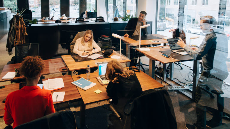 Medarbetare arbetar koncentrerat runt skrivbord på kontor