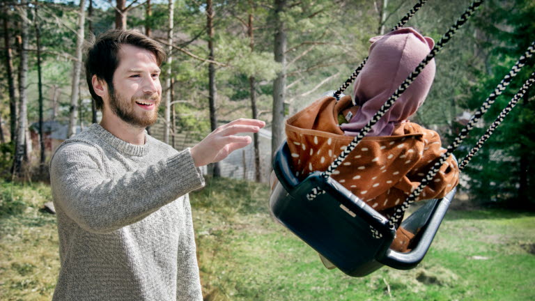 Man gungar barn utomhus i fint väder.