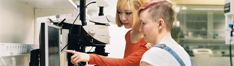 Två unga personer i ett laboratorium jobbar vid en dator.