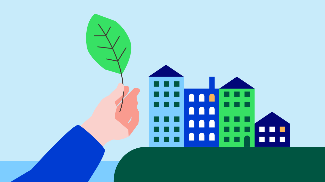 Hand som håller upp ett löv med stad i bakgrunden.