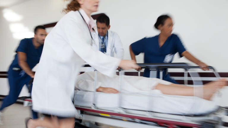 Läkare springer med patient i en korridor.