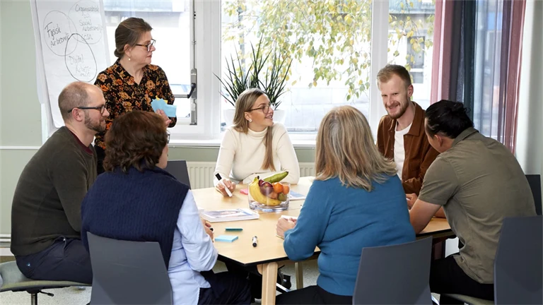 flera personer som sitter runt ett bord och pratar med varandra