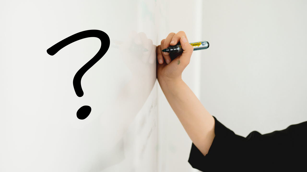 Hand ritar ett frågetecken med svart penna på whiteboardtavla