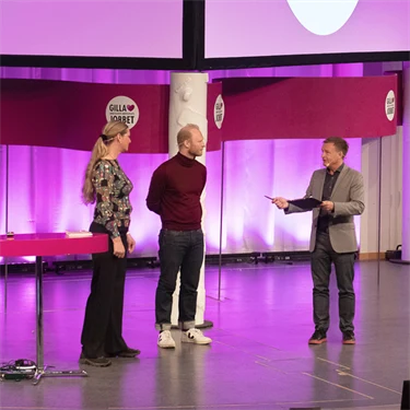 Två män och en kvinna på en stor scen inleder  arbetsmiljöeventet Gilla Jobbet 2022 i Folkets hus i Stockholm.