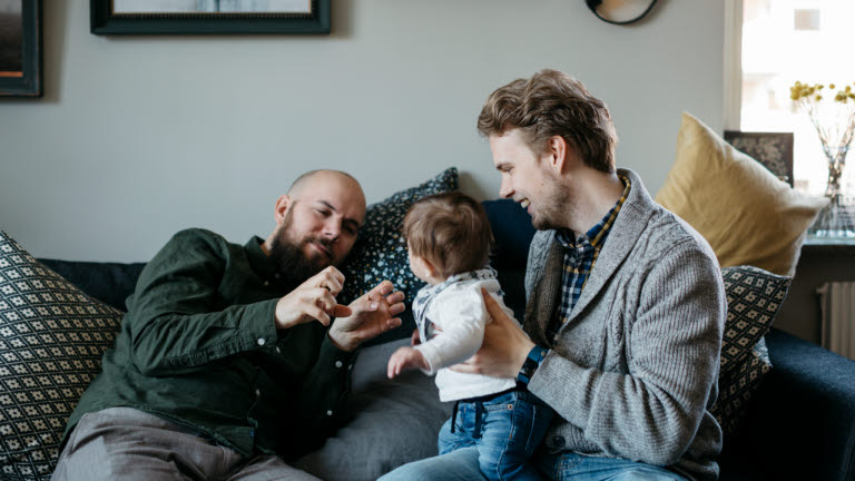 Två män leker med barn i soffa