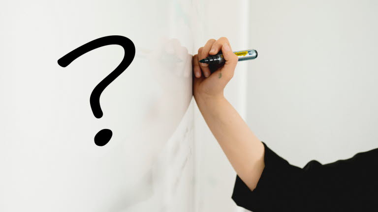Hand ritar ett frågetecken med svart penna på whiteboardtavla