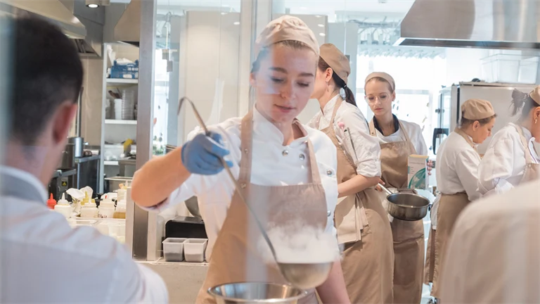 Restauranganställda lagar mat i köket.