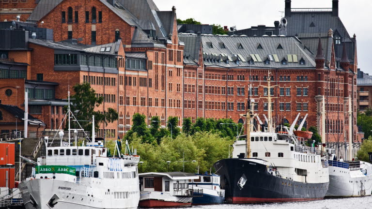 Münchenbryggeriets fasad med båtar i förgrunden.