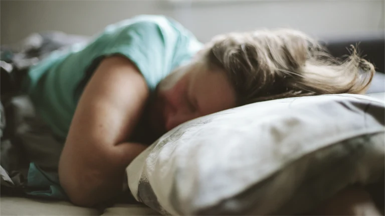 Kvinna som sover med huvudet på en kudde